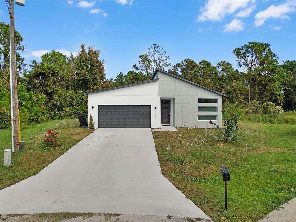 A modern single-story house with a two-tone exterior and a concrete driveway — 1187 N PLATTE LANE, POINCIANA, FL