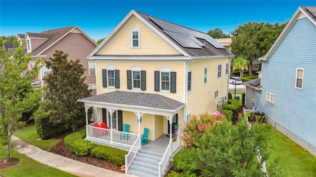 A yellow two-story house with a front porch, solar panels, and dark green shutters — 828 MORNING GLORY LANE, CELEBRATION, FL
