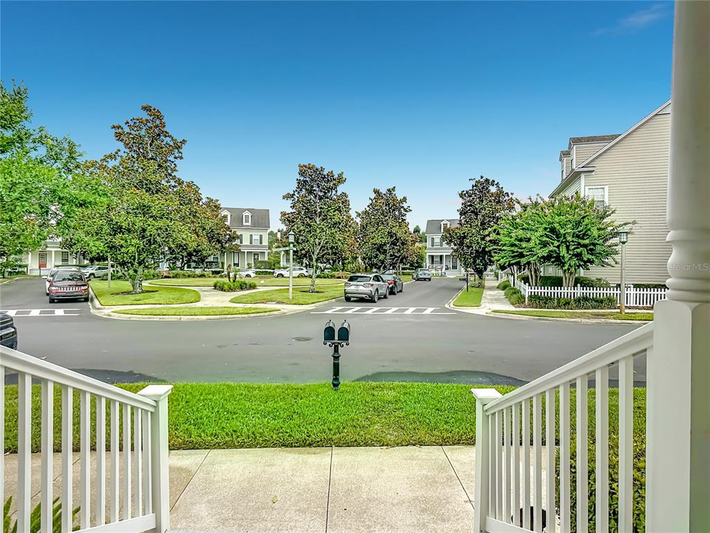 View from a front porch overlooking a suburban street with houses, trees, and parked cars — 828 MORNING GLORY LANE, CELEBRATION, FL