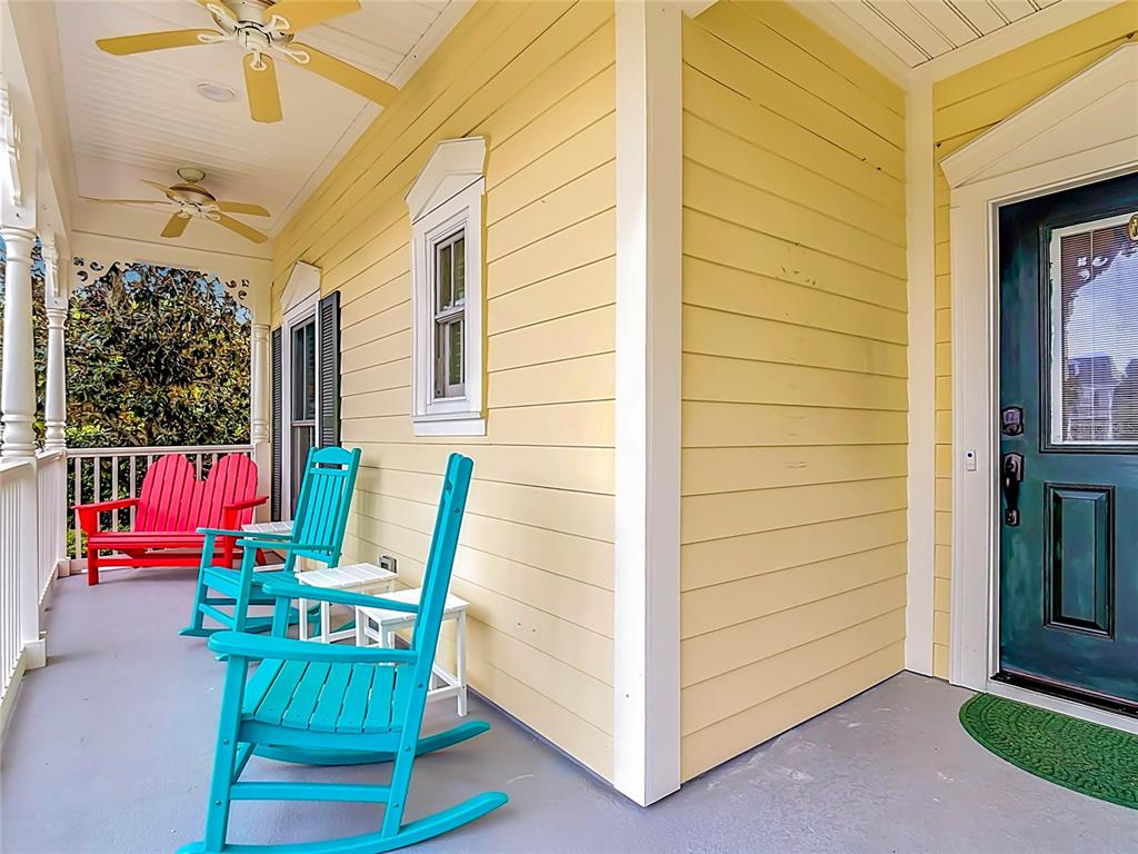 A yellow-sided porch features a dark green front door, two turquoise rockers, and a red bench — 828 MORNING GLORY LANE, CELEBRATION, FL