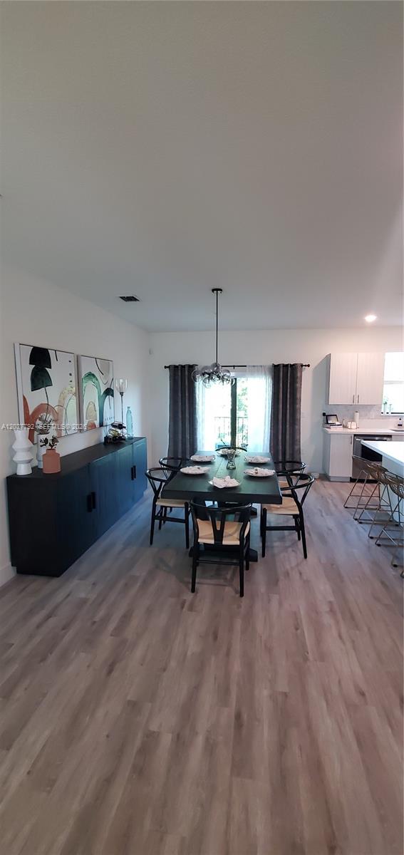A dining area features a dark table and chairs, a sideboard, and light wood flooring — 10473 NW 82nd St # 11, Doral FL 33178, DORAL, FL