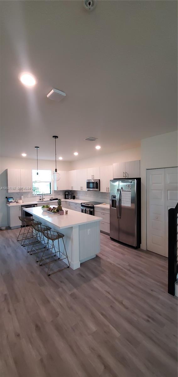 A modern kitchen features white cabinets, a central island with bar stools, and stainless appliances — 10473 NW 82nd St # 11, Doral FL 33178, DORAL, FL