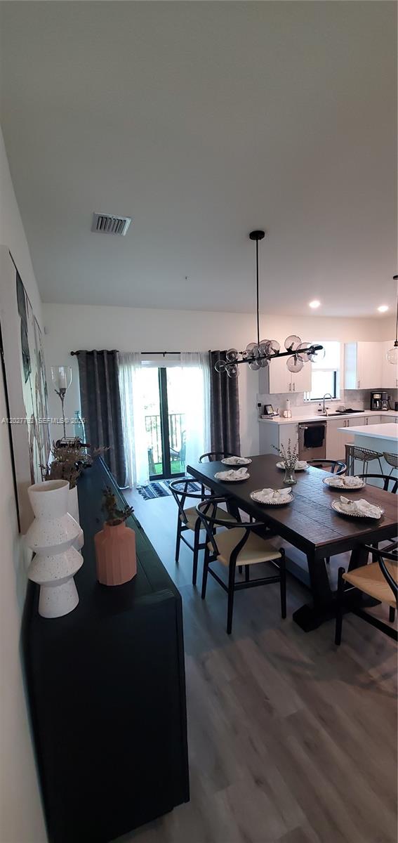 A dining area with a dark wood table, modern chandelier, and adjacent kitchen — 10473 NW 82nd St # 11, Doral FL 33178, DORAL, FL