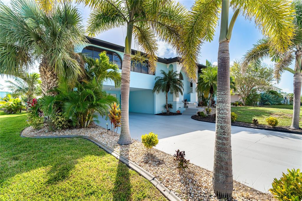A light blue two-story house features a covered ground-level parking area and palm trees — 10467 MARION STREET, ENGLEWOOD, FL