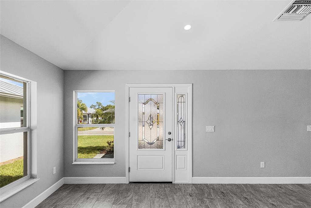 A bright entryway features gray walls, tile flooring, and a white front door with glass — 175 VILLAGE CIRCLE UNIT 32, LABELLE, FL
