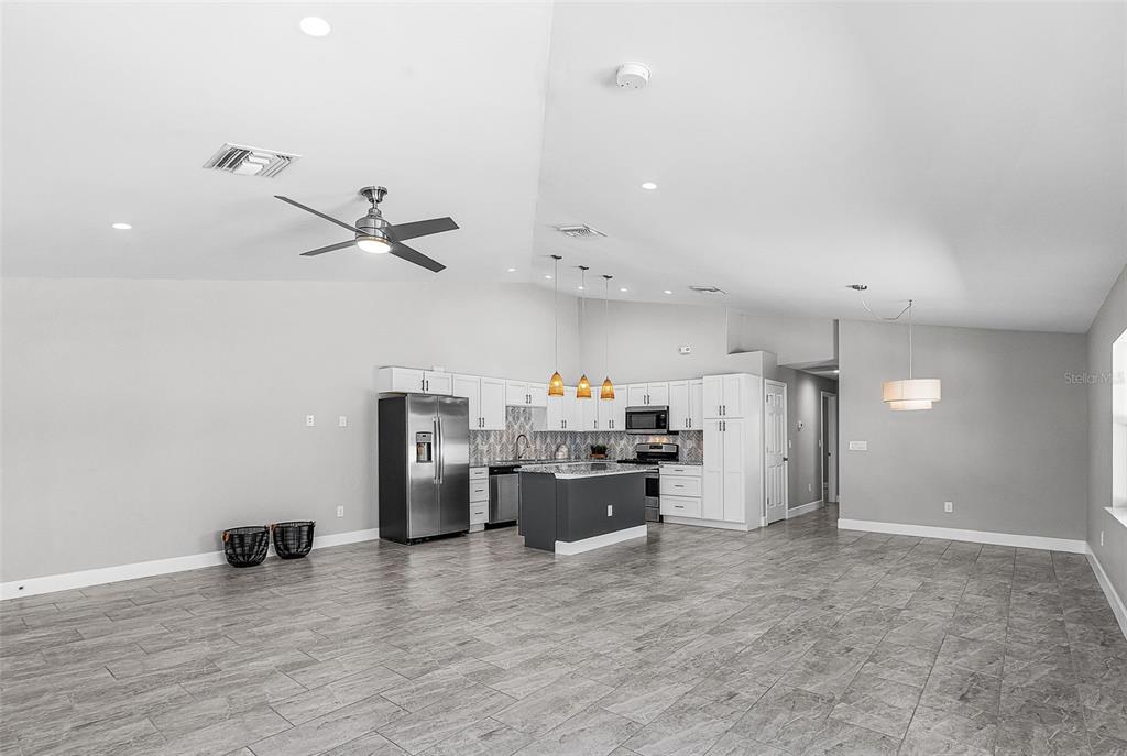 A kitchen with white cabinets, a dark island, and gray tile flooring in an open room — 175 VILLAGE CIRCLE UNIT 32, LABELLE, FL
