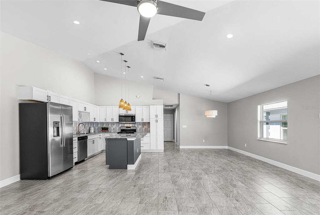 A modern kitchen with white cabinetry, a gray island, and tile flooring in an open room — 175 VILLAGE CIRCLE UNIT 32, LABELLE, FL