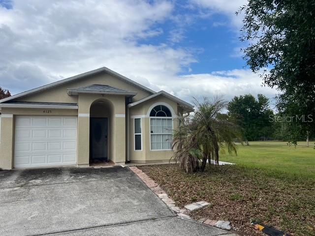 A single-story house with a white garage door, arched entryway, and a large front window — 4125 HAMPSHIRE VILLAGE COURT, ORLANDO, FL