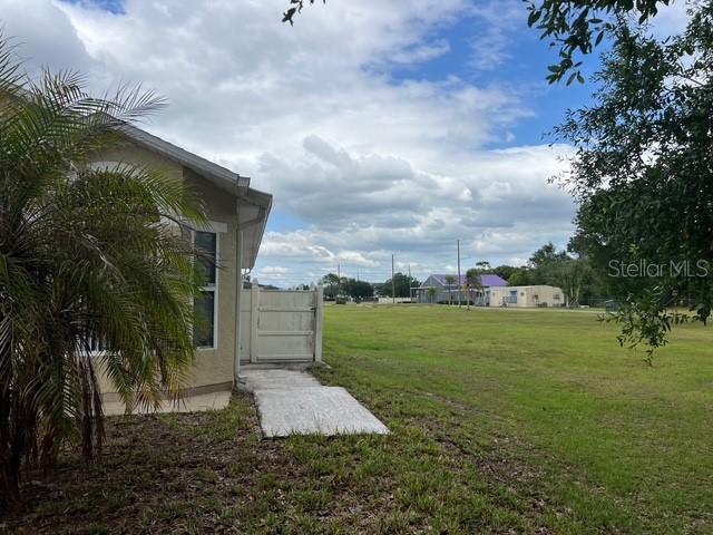 A side view of a house exterior shows a white fence and a large grassy field — 4125 HAMPSHIRE VILLAGE COURT, ORLANDO, FL