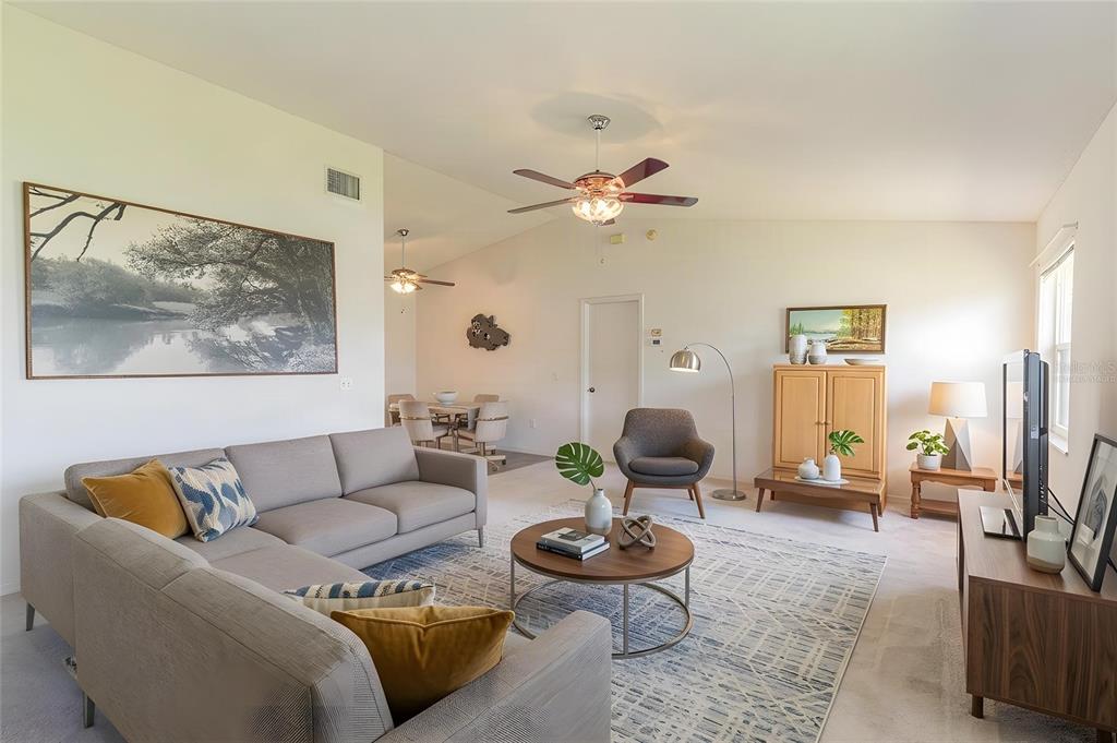 A living room features a grey sectional sofa, a round coffee table, and a dining area — 2260 GRAND CYPRESS DRIVE, LAKELAND, FL