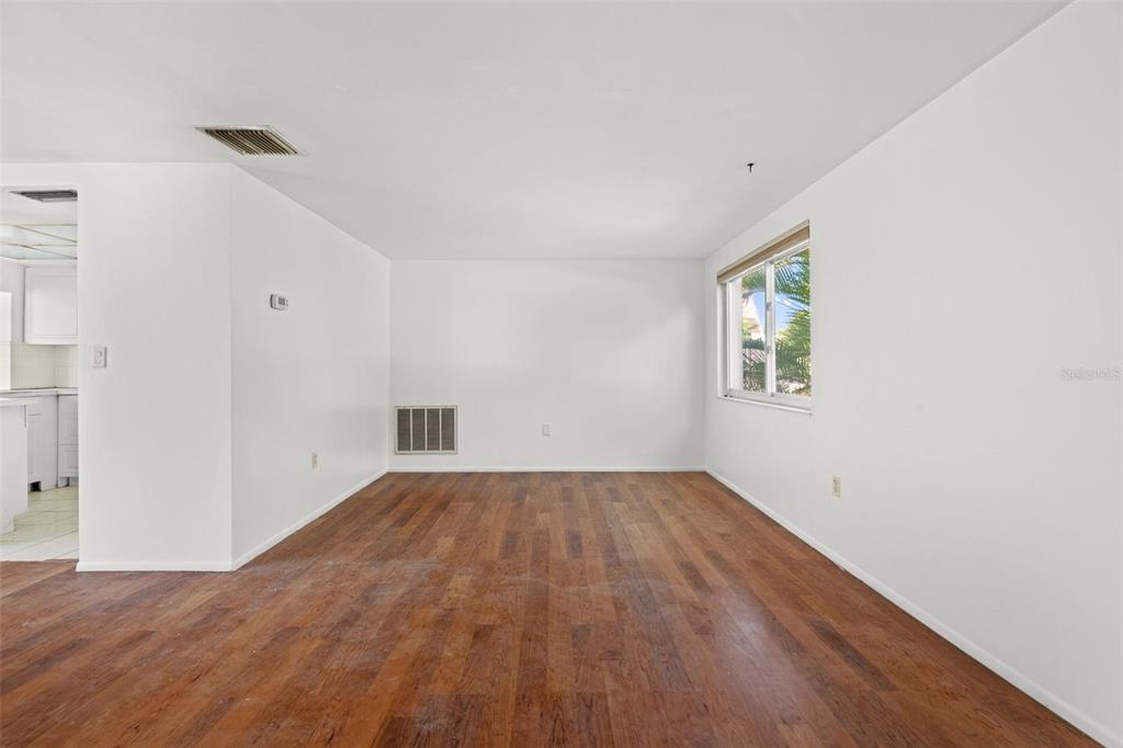 An empty room with white walls, wood-look flooring, a window, and a wall vent — 4312 NEWBURY DRIVE, NEW PORT RICHEY, FL