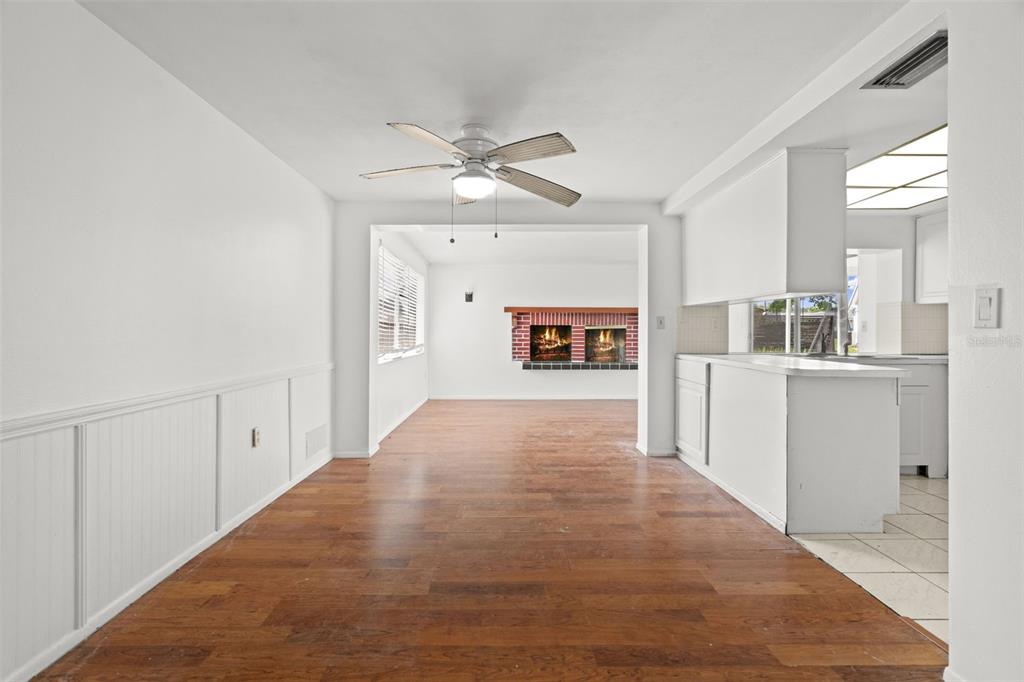 A dining area with wood flooring leads to a living room featuring a brick fireplace — 4312 NEWBURY DRIVE, NEW PORT RICHEY, FL