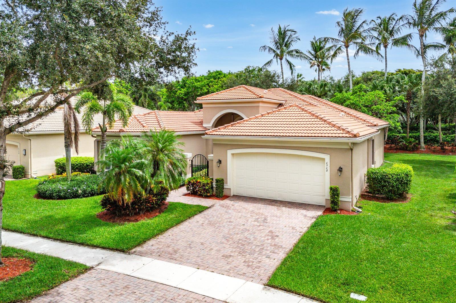 A single-story house with a beige stucco exterior, a tiled roof, and a paved driveway — 6968 Corning Circle, Boynton Beach FL 33437, BOYNTON BEACH, FL