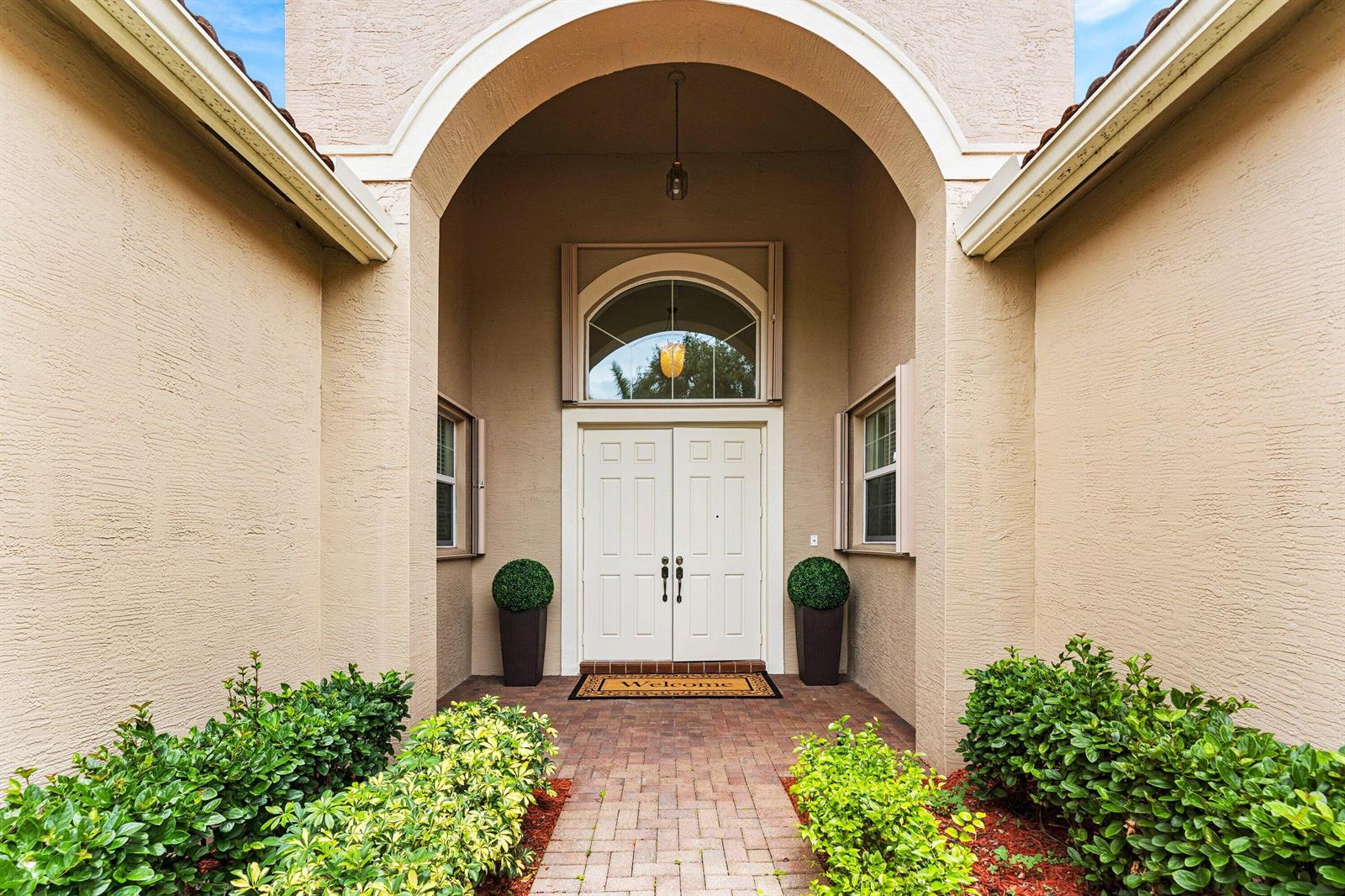 An arched entryway leads to a double front door with a semi-circular transom window — 6968 Corning Circle, Boynton Beach FL 33437, BOYNTON BEACH, FL