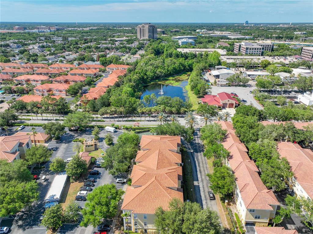 An aerial view shows a multi-story apartment complex with terracotta roofs near a pond — 1150 LAKE SHADOW CIRCLE UNIT 3304, MAITLAND, FL