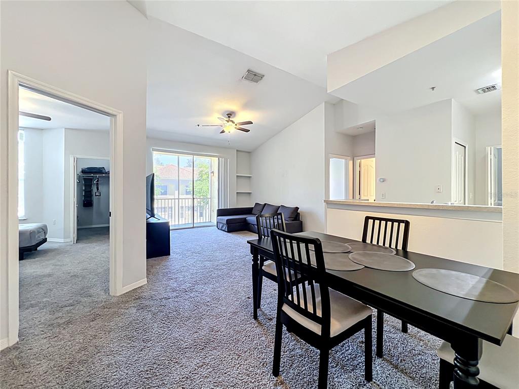 A dining area with a black table and chairs overlooks a living room with carpet — 1150 LAKE SHADOW CIRCLE UNIT 3304, MAITLAND, FL