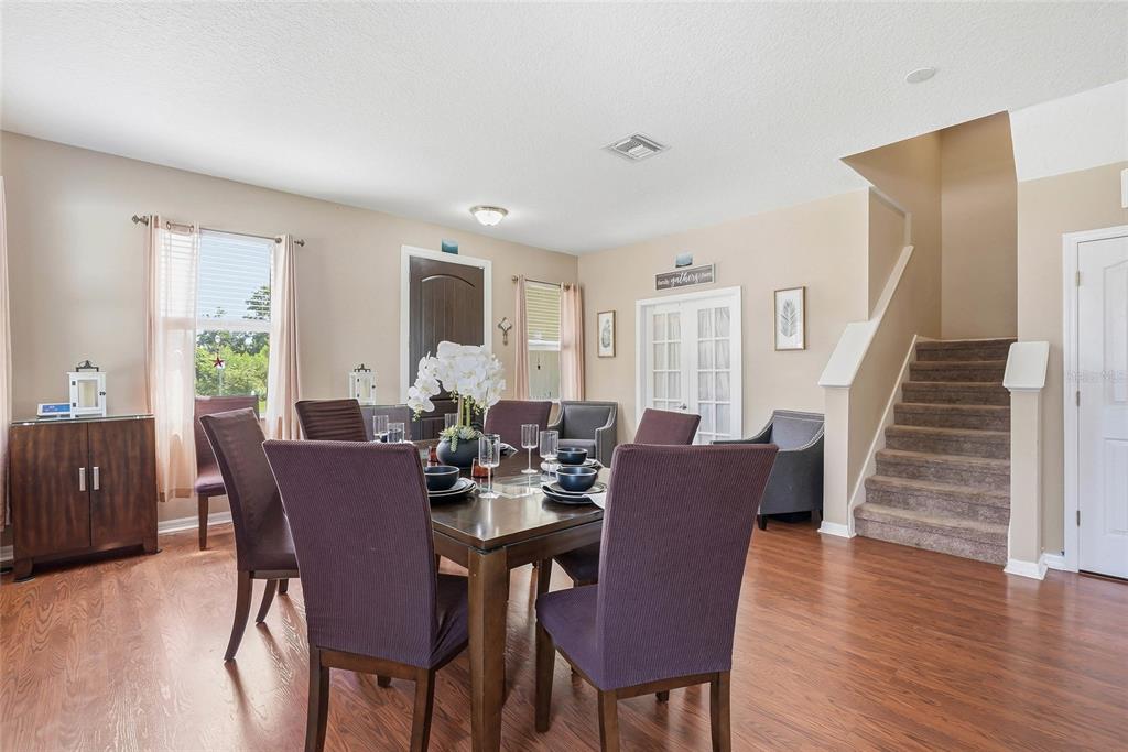 A dining room features a wooden table with purple chairs, wood flooring, and a staircase — 5213 PRAIRIE VIEW WAY, WESLEY CHAPEL, FL