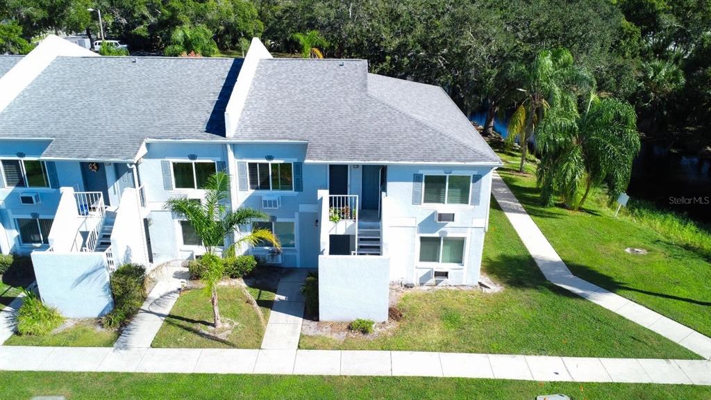 An aerial view of a two-story light blue townhouse with a gray shingled roof — 4148 DOLPHIN DRIVE UNIT 3, TAMPA, FL