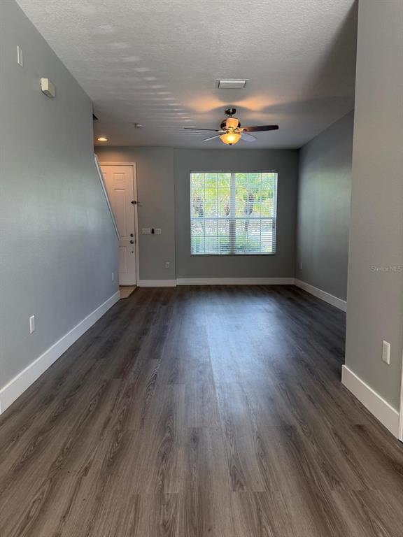 An empty room with gray walls, wood-look flooring, a ceiling fan, and a front door — 11503 DECLARATION DRIVE, TAMPA, FL