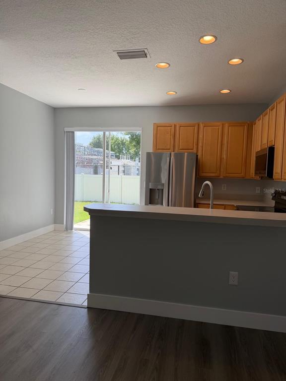 A kitchen with wood cabinets and stainless steel appliances overlooks a tiled dining area — 11503 DECLARATION DRIVE, TAMPA, FL