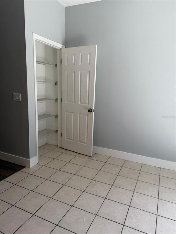 A room with light gray walls, tiled flooring, and an open door to a pantry — 11503 DECLARATION DRIVE, TAMPA, FL
