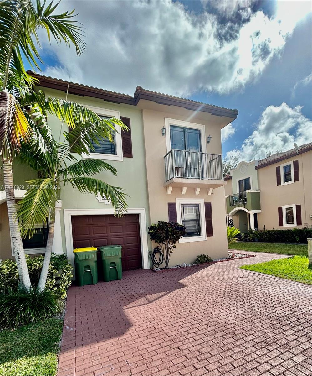 A two-story townhouse with a brick driveway, a garage, and a second-floor balcony — 607 NE 35th Ave # 607, Homestead FL 33033, HOMESTEAD, FL