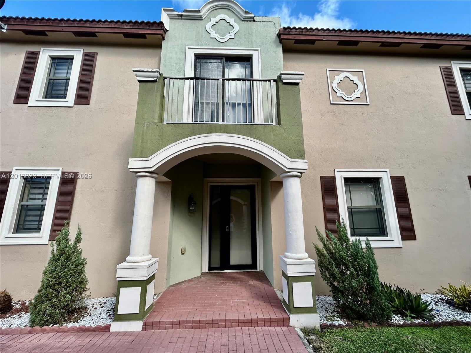 The exterior of a two-story house features a covered entryway with columns and a balcony — 607 NE 35th Ave # 607, Homestead FL 33033, HOMESTEAD, FL