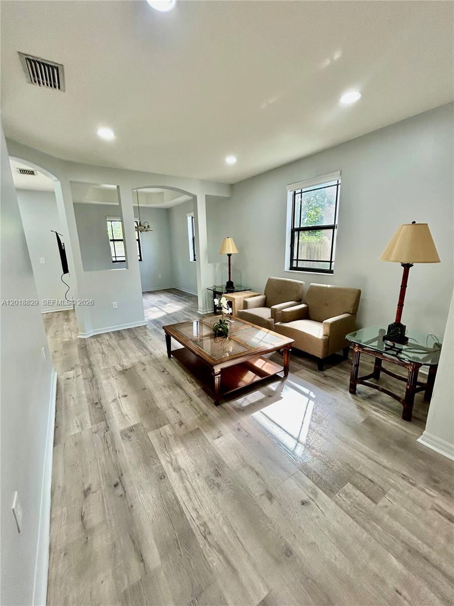 A living room features light wood-look flooring, two beige armchairs, and a wooden coffee table — 607 NE 35th Ave # 607, Homestead FL 33033, HOMESTEAD, FL