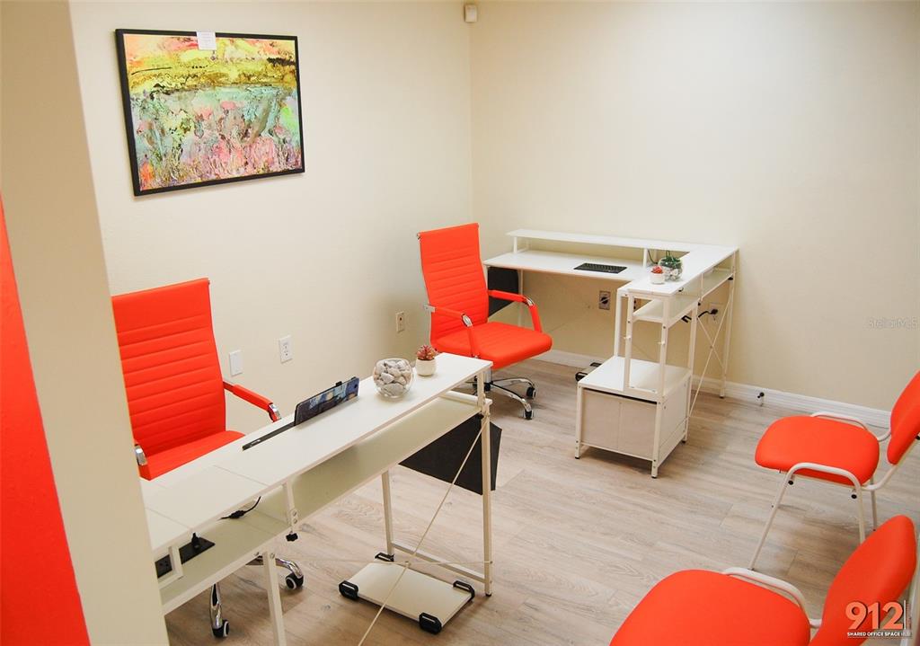 An office room features two white desks, four orange chairs, and a framed wall painting — 912 DREW STREET STREET, CLEARWATER, FL