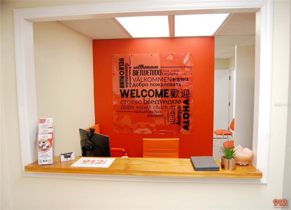 A reception area features a wooden counter in front of an orange wall with a multilingual welcome sign — 912 DREW STREET STREET, CLEARWATER, FL