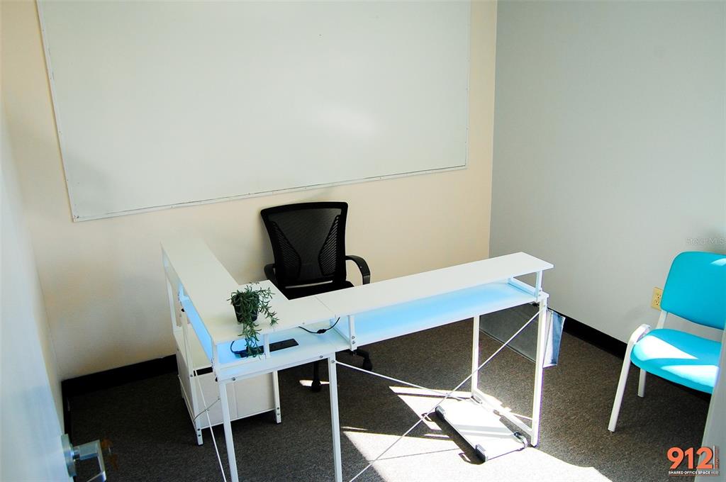 A small office features a white L-shaped desk, a black chair, and a whiteboard — 912 DREW STREET STREET, CLEARWATER, FL