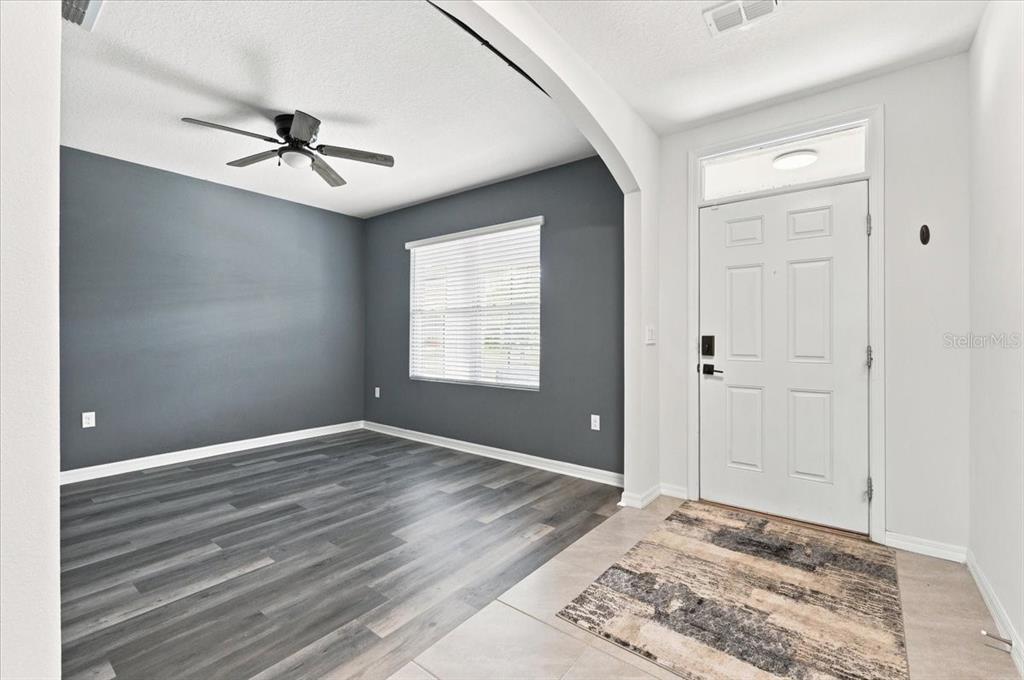An entryway leads into a room with dark gray walls, wood-look flooring, and a ceiling fan — 2934 LONG POND DRIVE, LAKELAND, FL