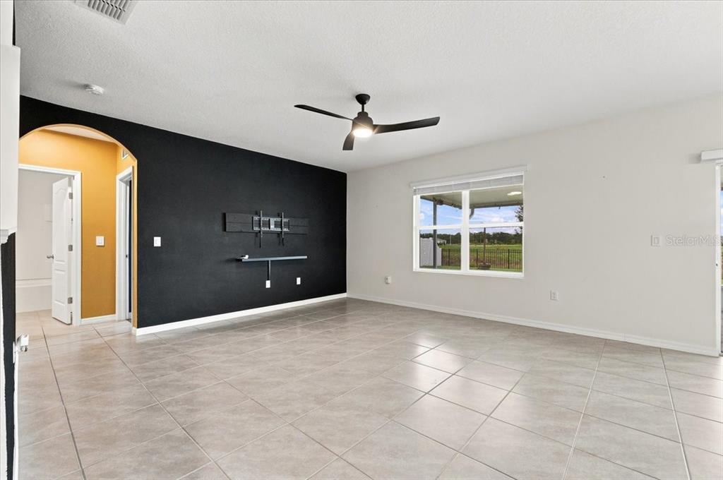 A living room features light tile flooring, a black accent wall, and a ceiling fan — 2934 LONG POND DRIVE, LAKELAND, FL