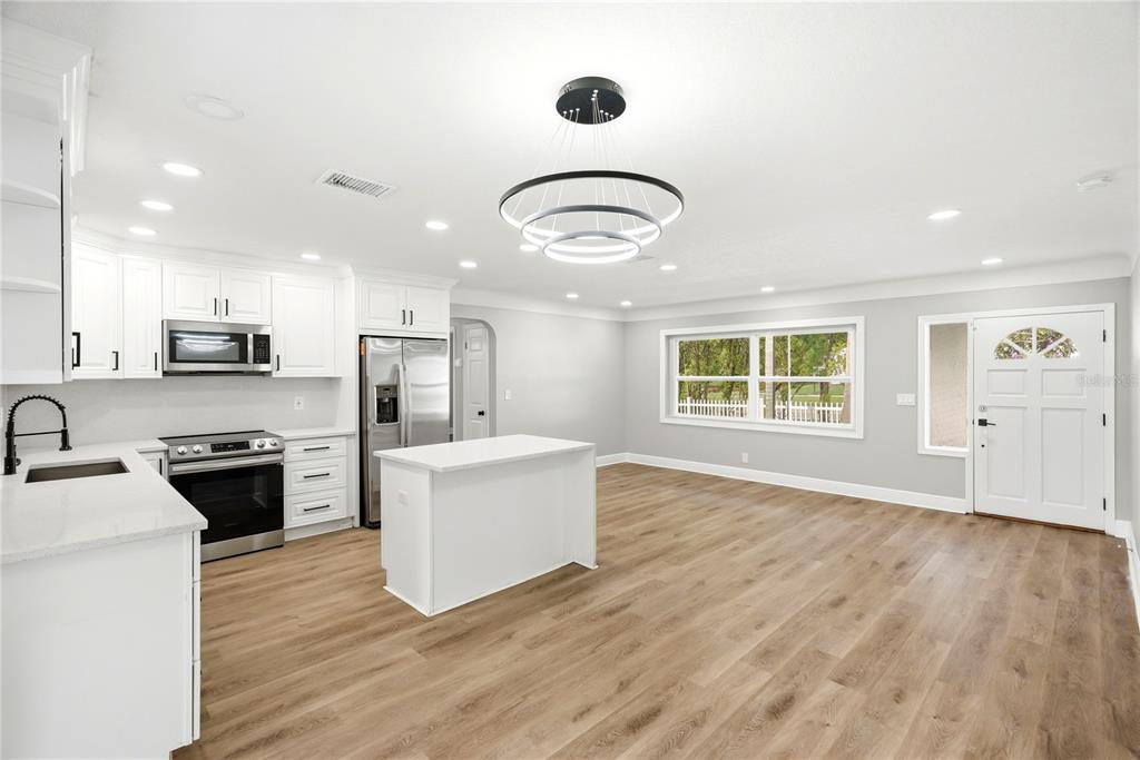A modern kitchen features white cabinets, stainless steel appliances, a center island, and wood flooring — 1628 S HIGHLAND AVENUE, CLEARWATER, FL