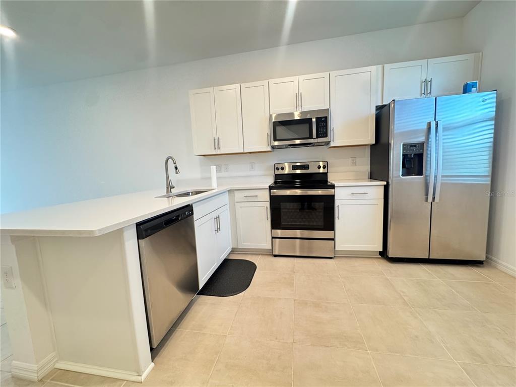 A kitchen features white cabinets, stainless steel appliances, and a peninsula with a sink — 8528 DAYBREAK STREET, SARASOTA, FL