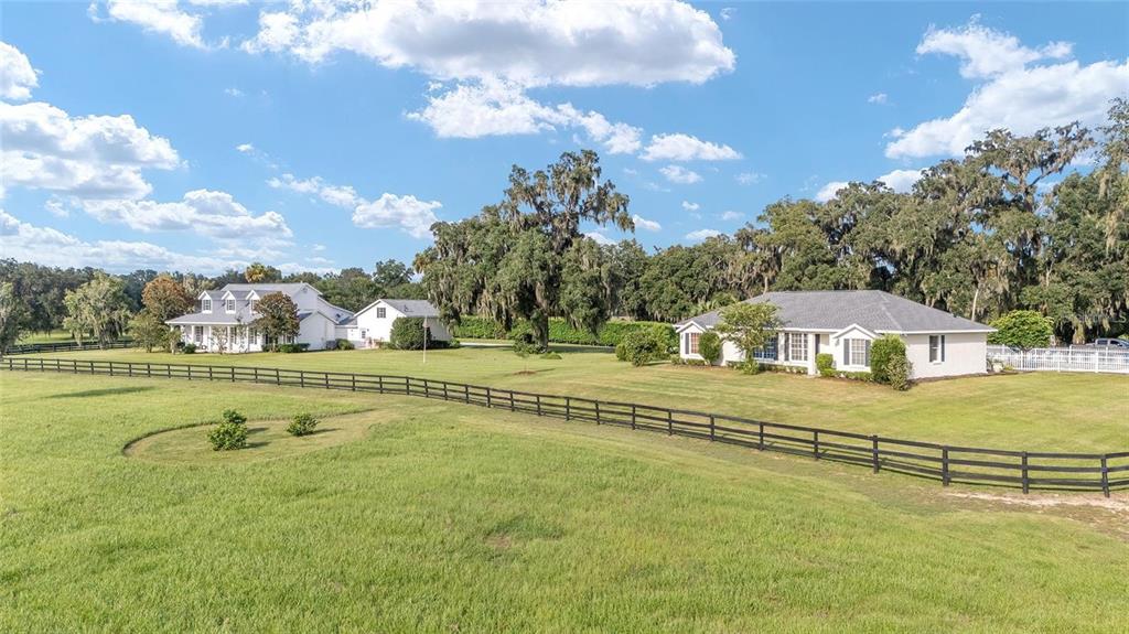 Two houses sit on a large grassy lot enclosed by a black wooden fence — 7137 & 7141 S MAGNOLIA AVENUE, OCALA, FL