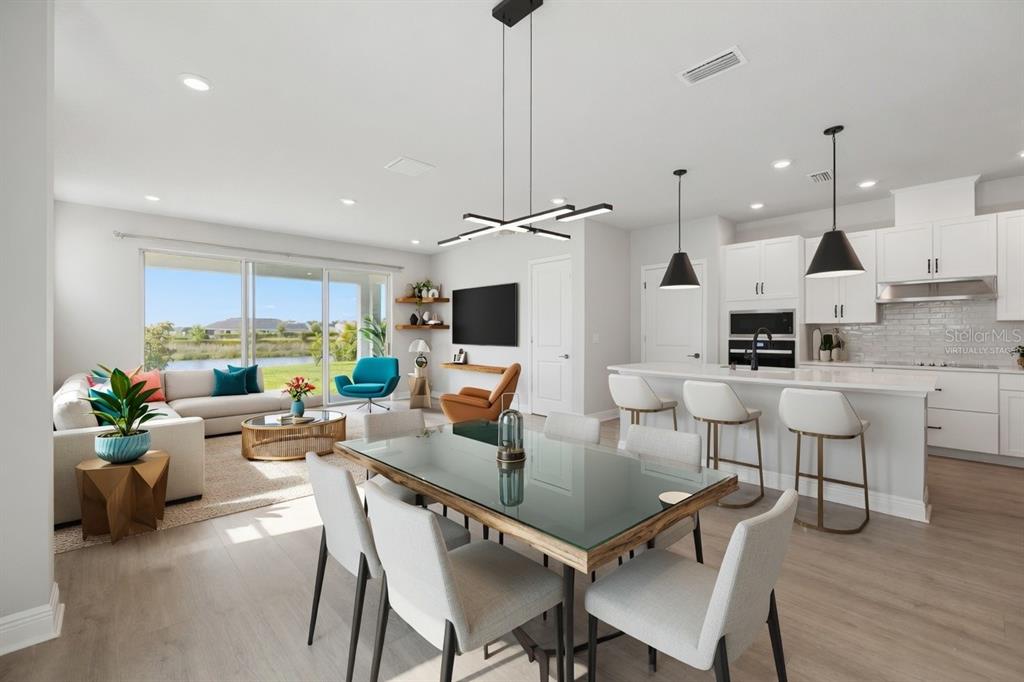 An open-concept living, dining, and kitchen area with light wood floors and a waterfront view — 11832 CATAWBA COVE, PARRISH, FL