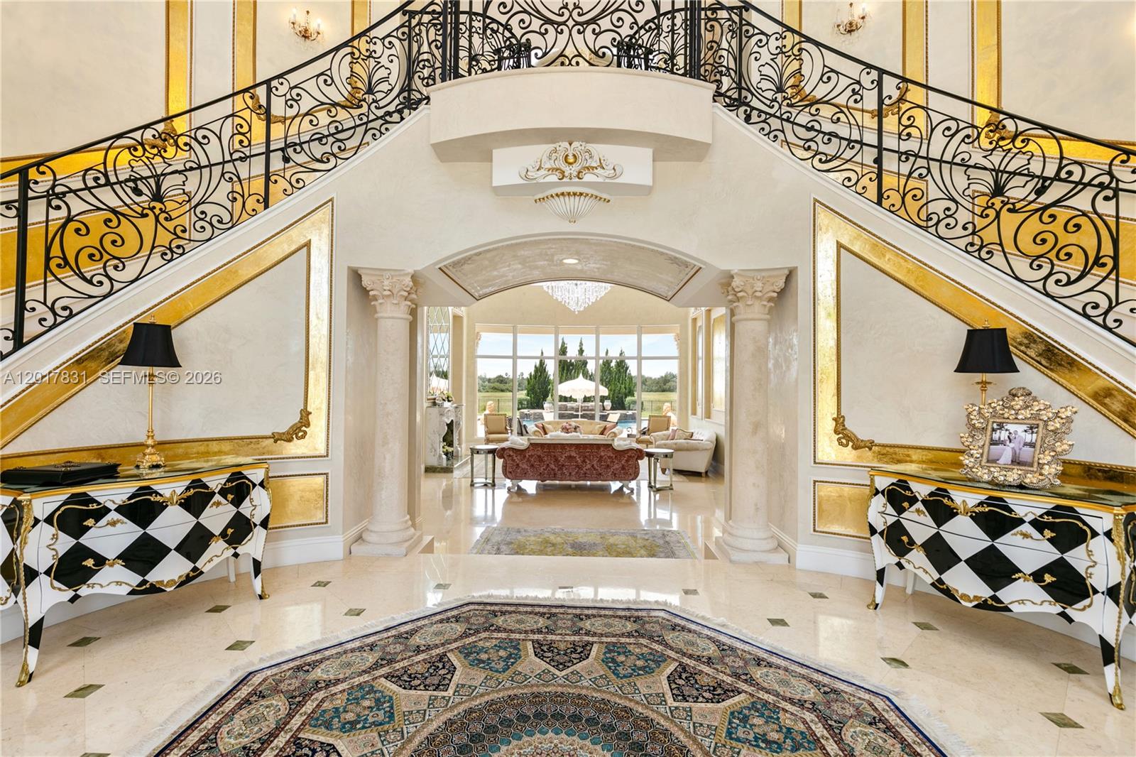 A grand foyer features a double staircase, checkered cabinets, and a view into a living area — 2951 Lake Ridge Ln, Weston FL 33332, WESTON, FL