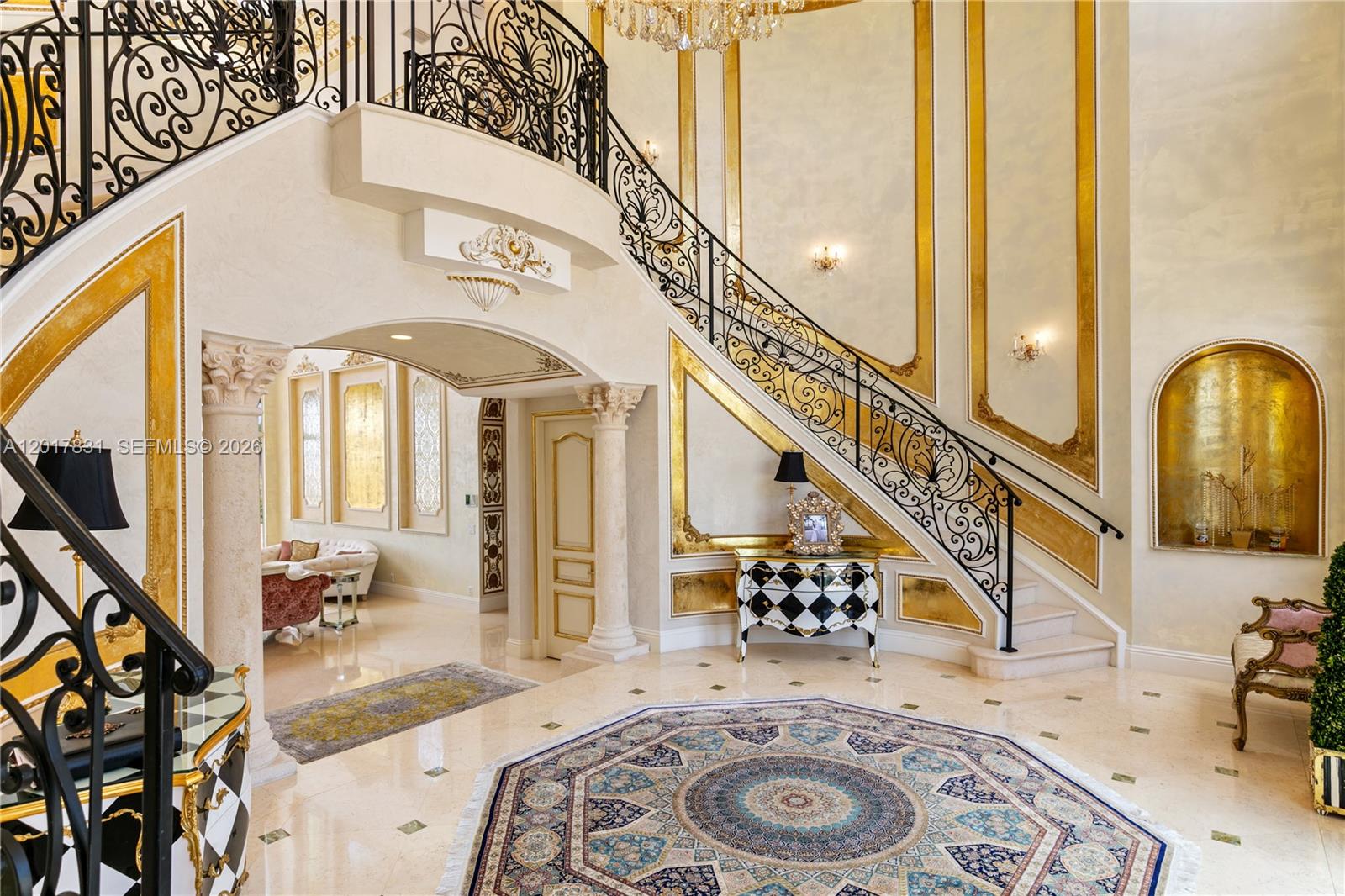 A grand foyer features a curved staircase with ornate iron railings and gold-accented walls — 2951 Lake Ridge Ln, Weston FL 33332, WESTON, FL