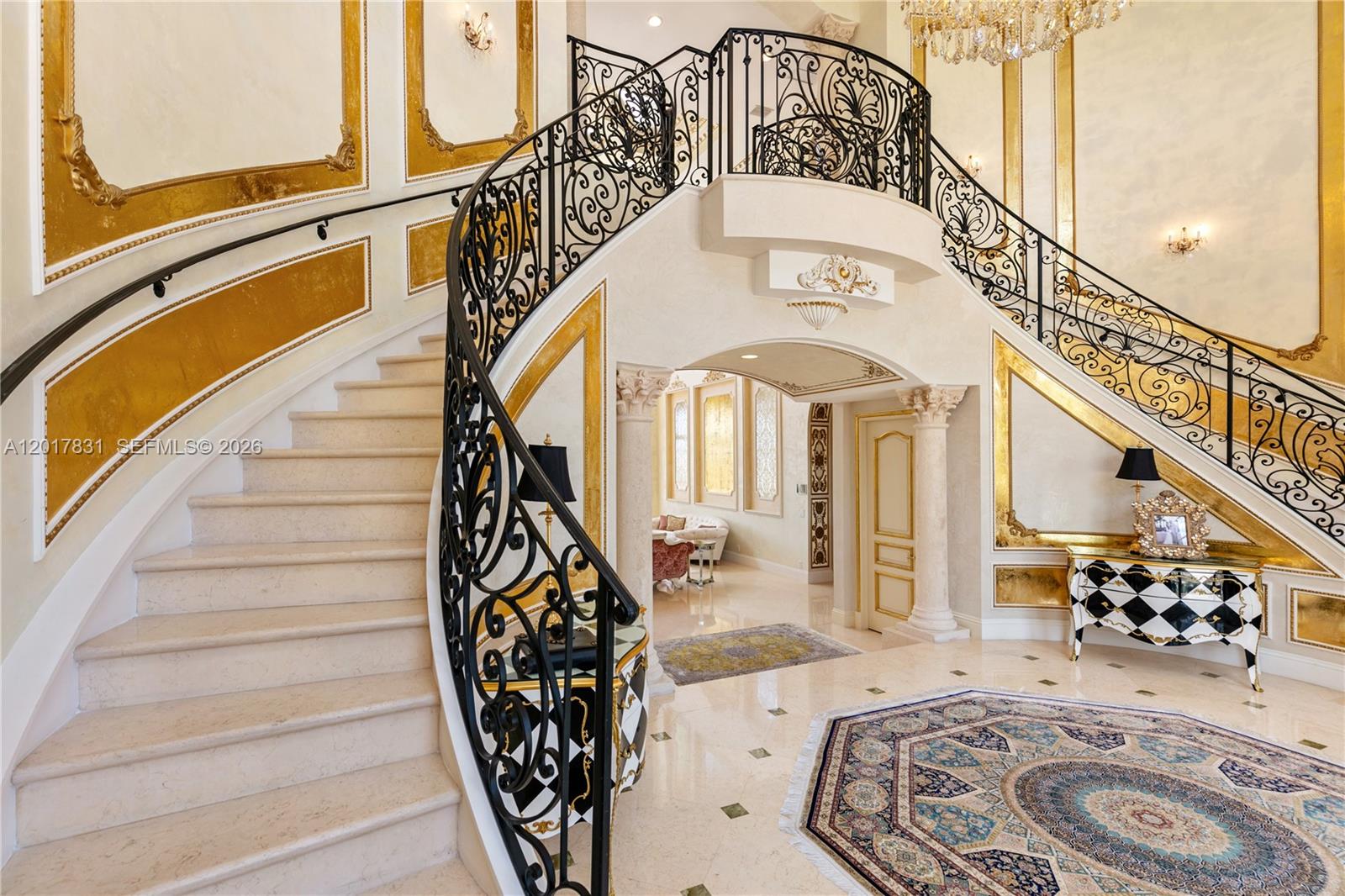A grand foyer features a curved double staircase with ornate black iron railings and gold-accented walls — 2951 Lake Ridge Ln, Weston FL 33332, WESTON, FL
