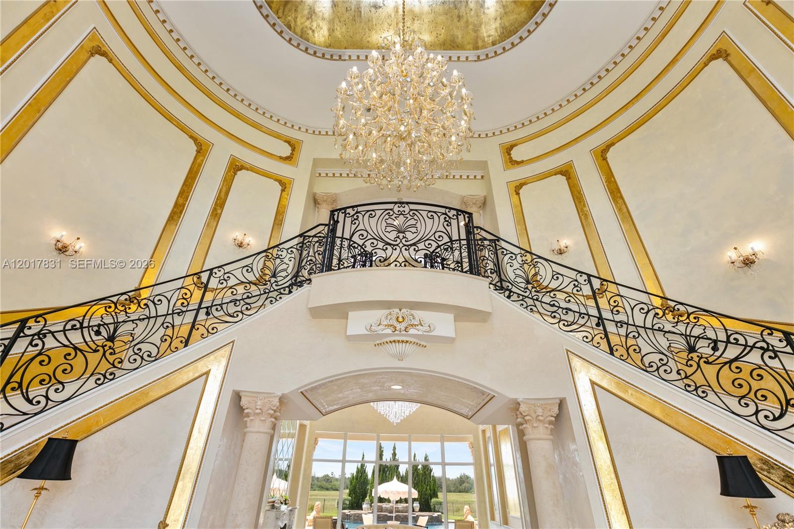 A grand foyer features a double staircase, ornate iron railings, and a large crystal chandelier — 2951 Lake Ridge Ln, Weston FL 33332, WESTON, FL