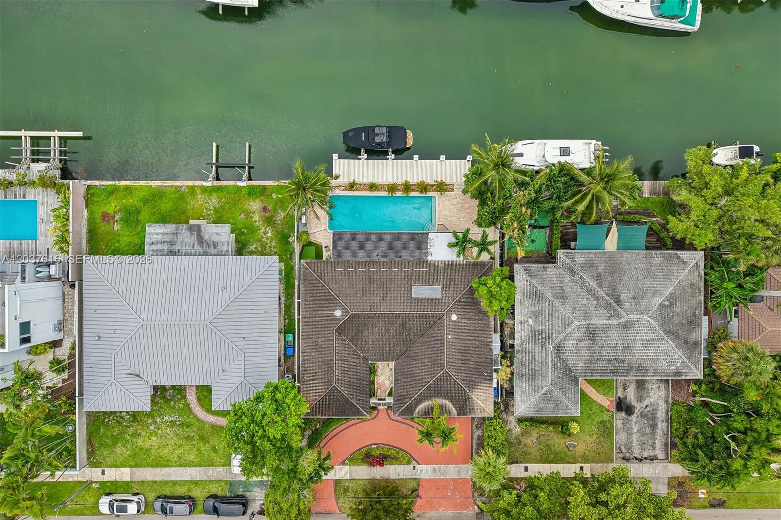 An aerial view shows three waterfront houses with pools, docks, and boats along a canal — 1140 NE 87th St, Miami FL 33138, MIAMI, FL