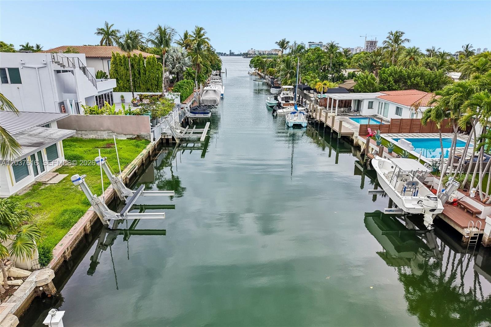 An aerial view shows a narrow canal lined with houses, boat lifts, and private docks — 1140 NE 87th St, Miami FL 33138, MIAMI, FL