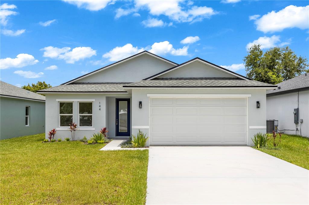 A single-story house with light gray stucco, a white garage door, and a blue front door — 144 11TH AVENUE, OSTEEN, FL