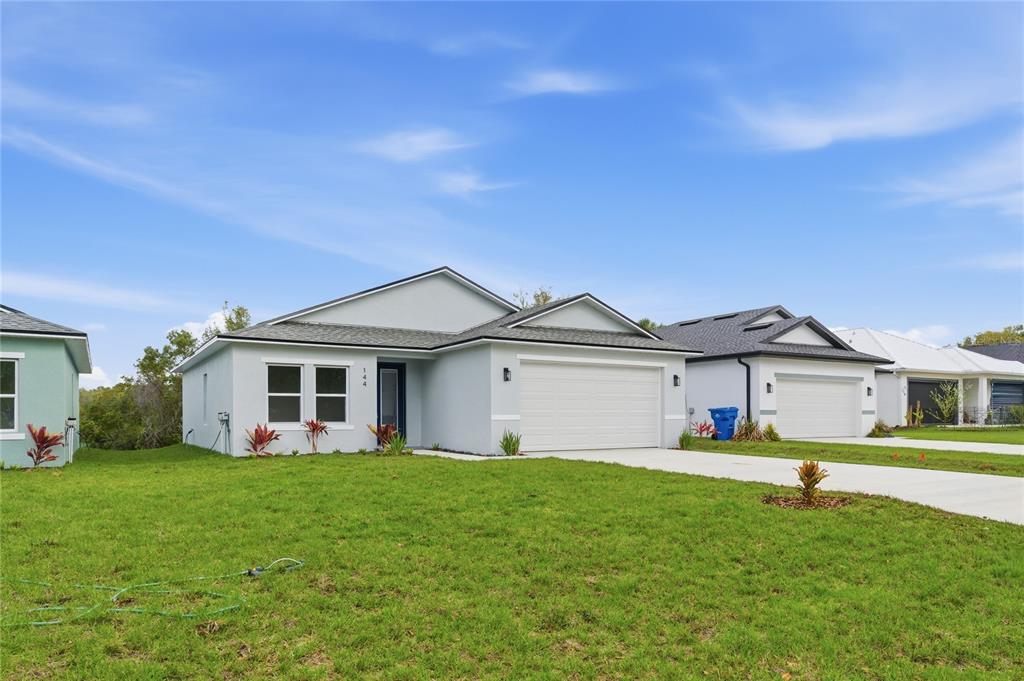 A light gray single-story house with a two-car garage and a front lawn — 144 11TH AVENUE, OSTEEN, FL