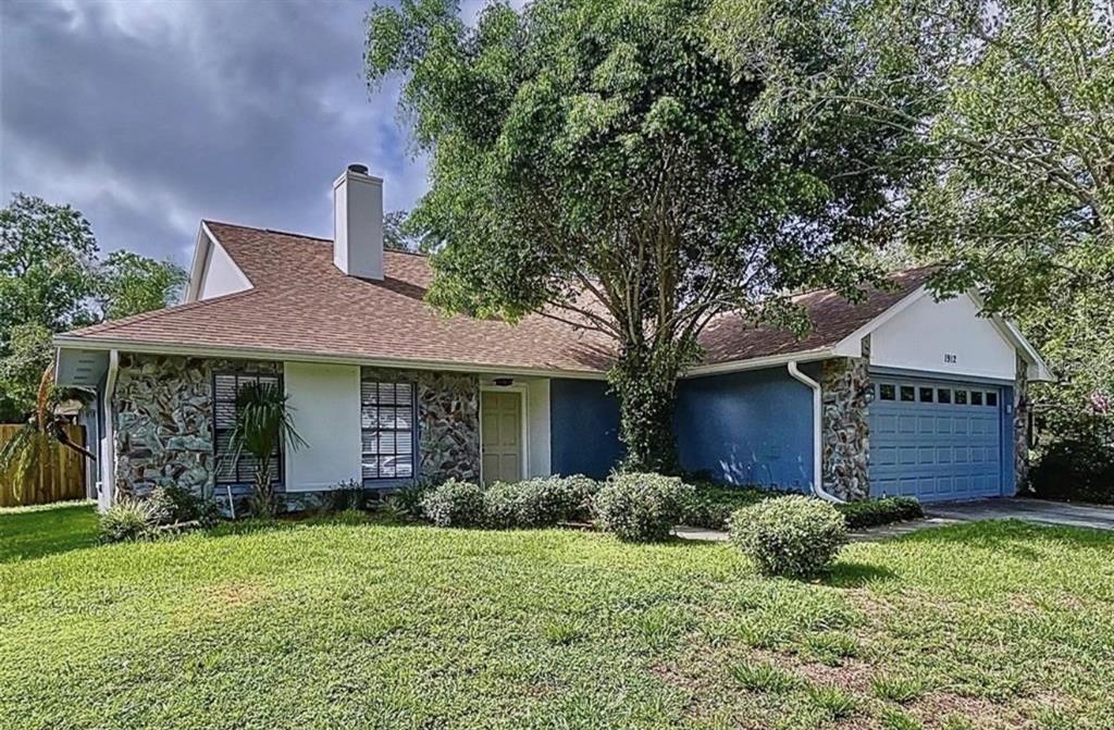 A single-story house with a stone facade, blue siding, a two-car garage, and a chimney — 1912 FIRETHORN COURT, BRANDON, FL