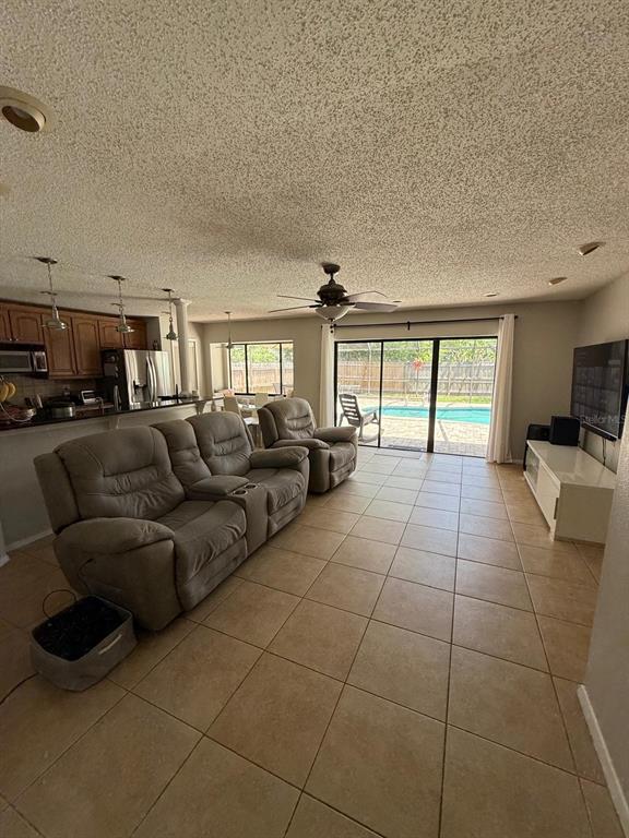 A living room with tile floors, a reclining sofa, and sliding doors opening to a pool — 1912 FIRETHORN COURT, BRANDON, FL