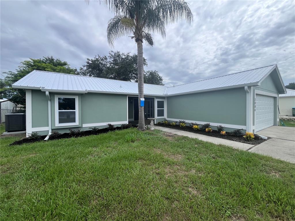 A single-story house with light green siding, a metal roof, and a palm tree — 3804 CAMBAY STREET, DELTONA, FL