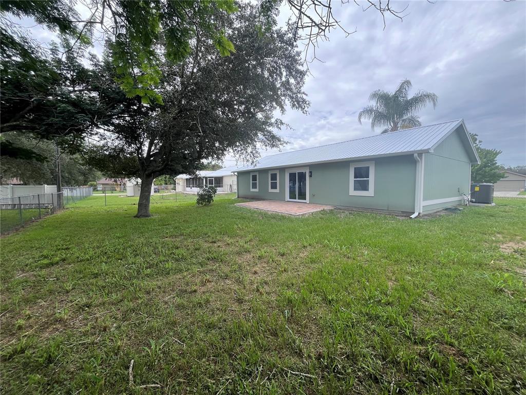 The exterior of a light green house with a metal roof and a brick patio — 3804 CAMBAY STREET, DELTONA, FL