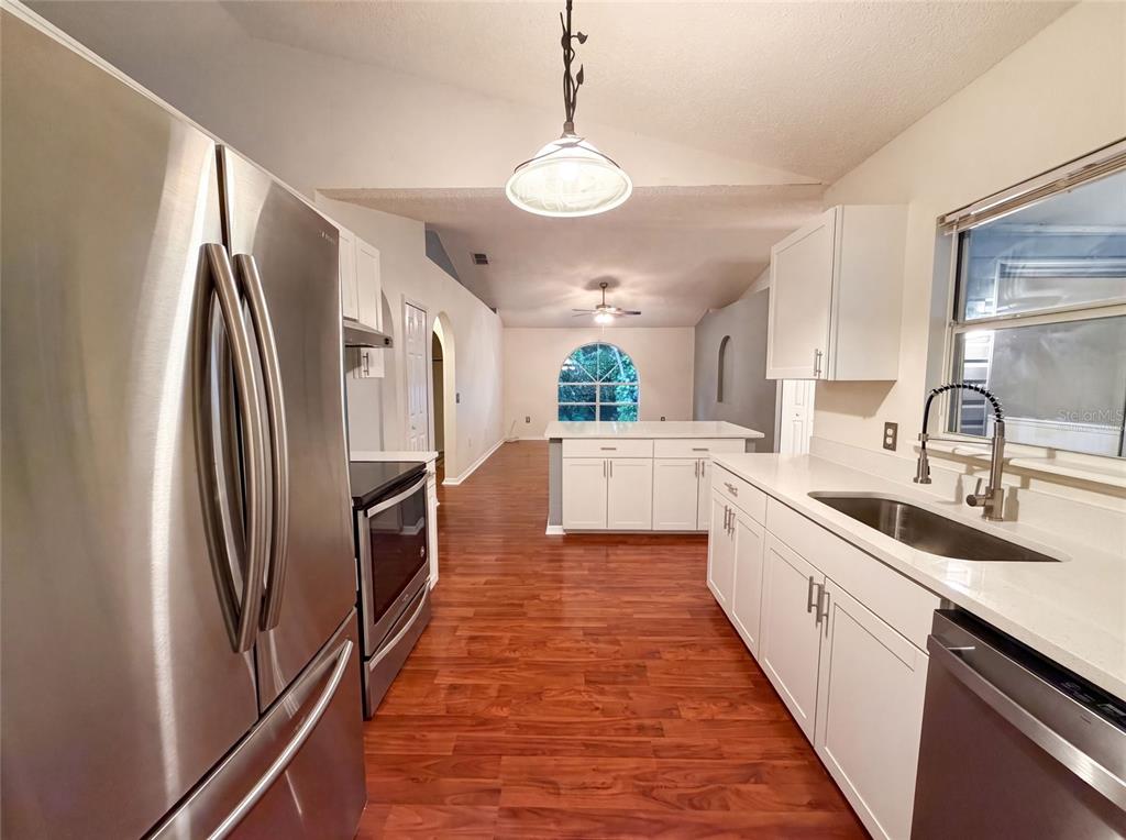 A kitchen with white cabinets, stainless steel appliances, and wood-look flooring — 29 VALENCIA CIRCLE, DEBARY, FL